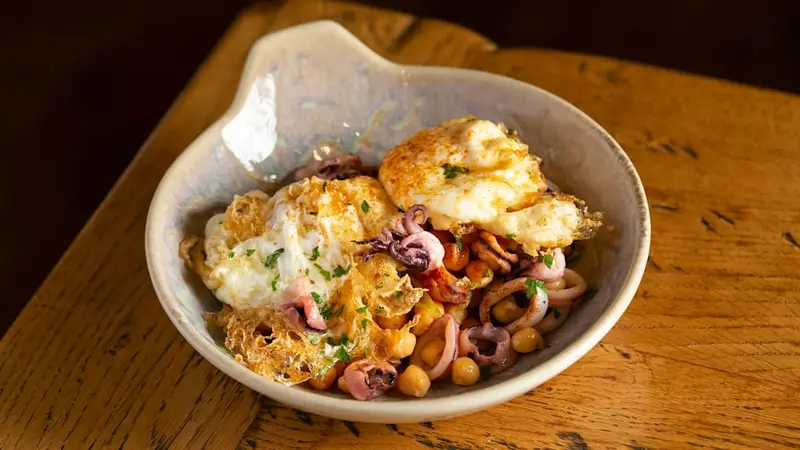 Huevos fritos sobre garbanzos de l'Anoia y chipirones salteados